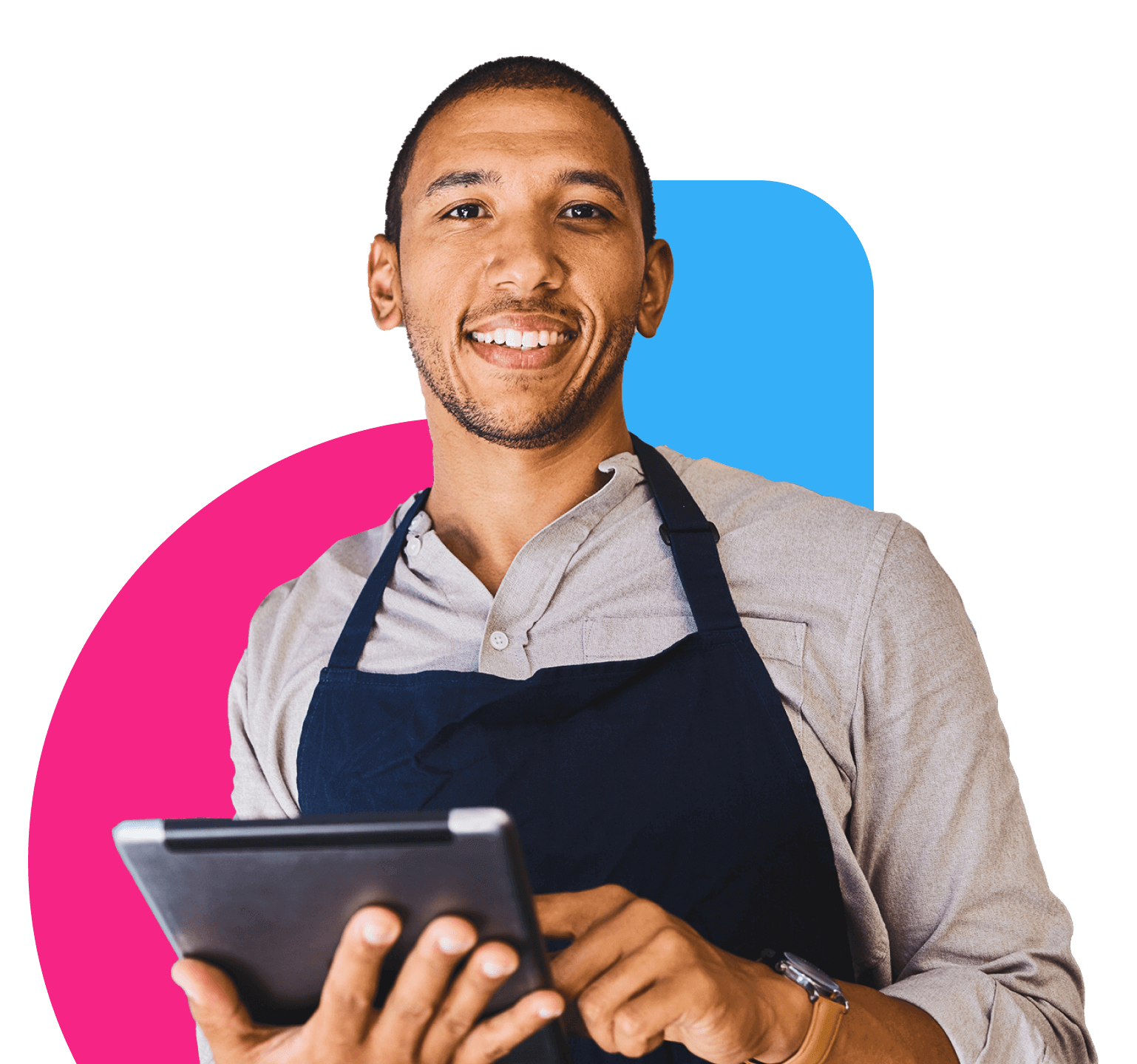 A young black man holding a tablet smiling at the camera, wearing a button down shirt and an apron